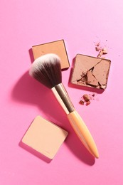 Photo of Refill pans of cosmetic products and brush on pink background, flat lay