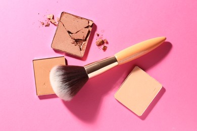 Photo of Refill pans of cosmetic products and brush on pink background, flat lay