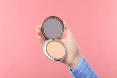 Photo of Woman holding open face powder with mirror on pink background, closeup