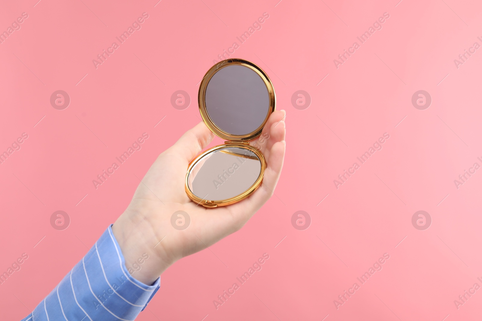 Woman holding open pocket mirror on pink background, closeup. Space for text Photo of Woman holding open pocket mirror on pink background, closeup. Space for text