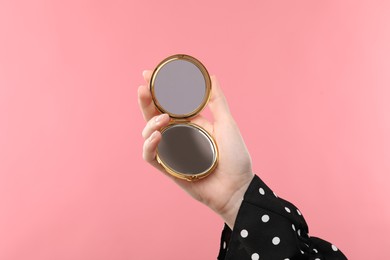Photo of Woman holding open pocket mirror on pink background, closeup
