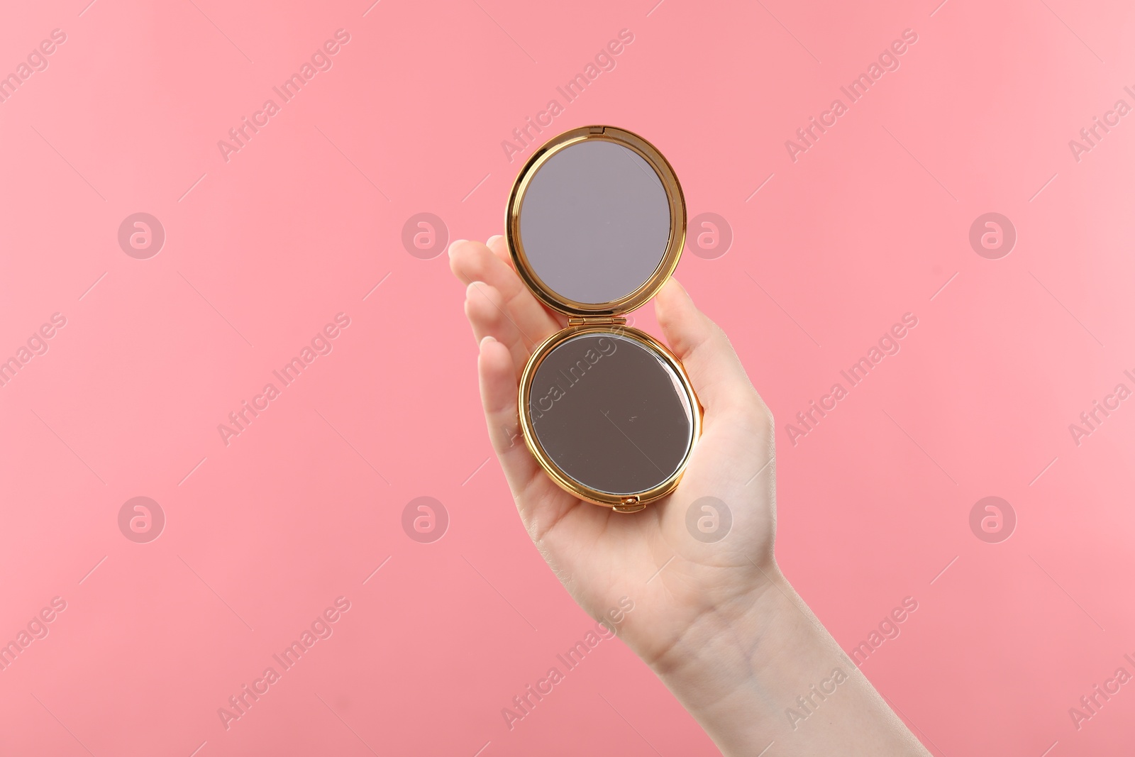 Woman holding open pocket mirror on pink background, closeup. Space for text Photo of Woman holding open pocket mirror on pink background, closeup. Space for text