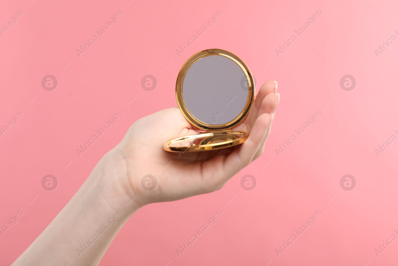 Woman holding open pocket mirror on pink background, closeup Photo of Woman holding open pocket mirror on pink background, closeup