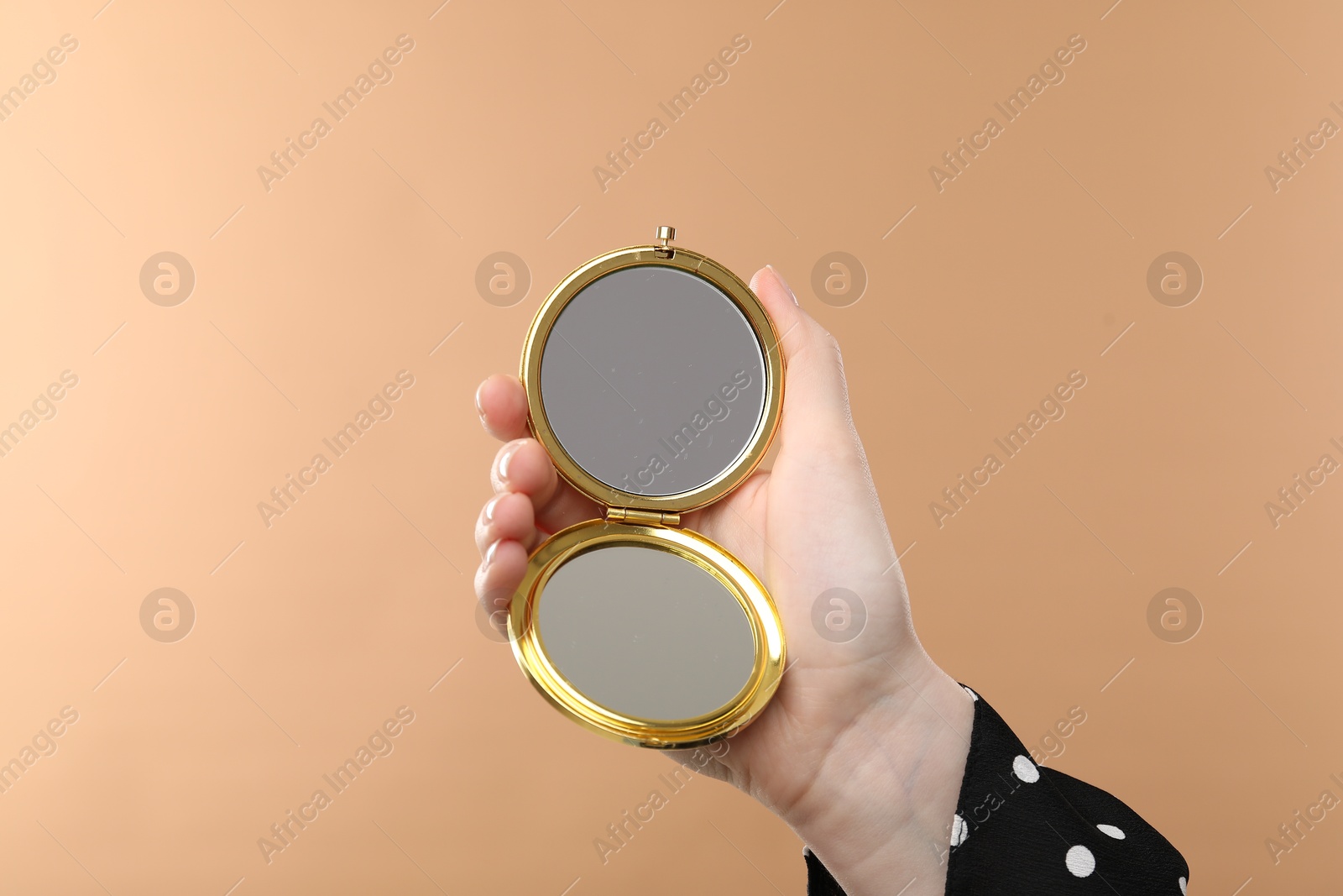 Woman holding open pocket mirror on beige background, closeup Photo of Woman holding open pocket mirror on beige background, closeup
