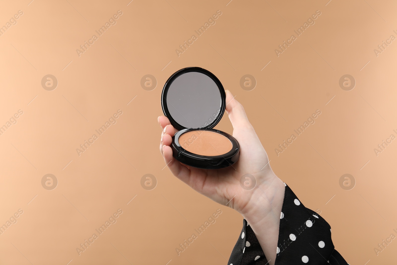 Woman holding open face powder with mirror on beige background, closeup Photo of Woman holding open face powder with mirror on beige background, closeup