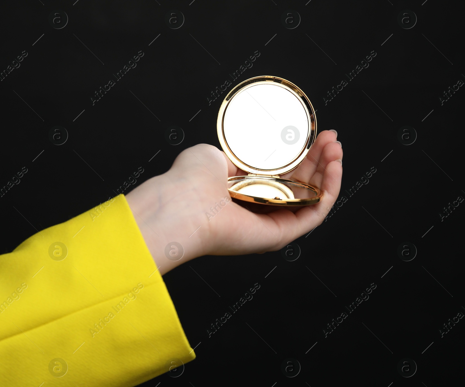 Photo of Woman holding open pocket mirror on black background, closeup