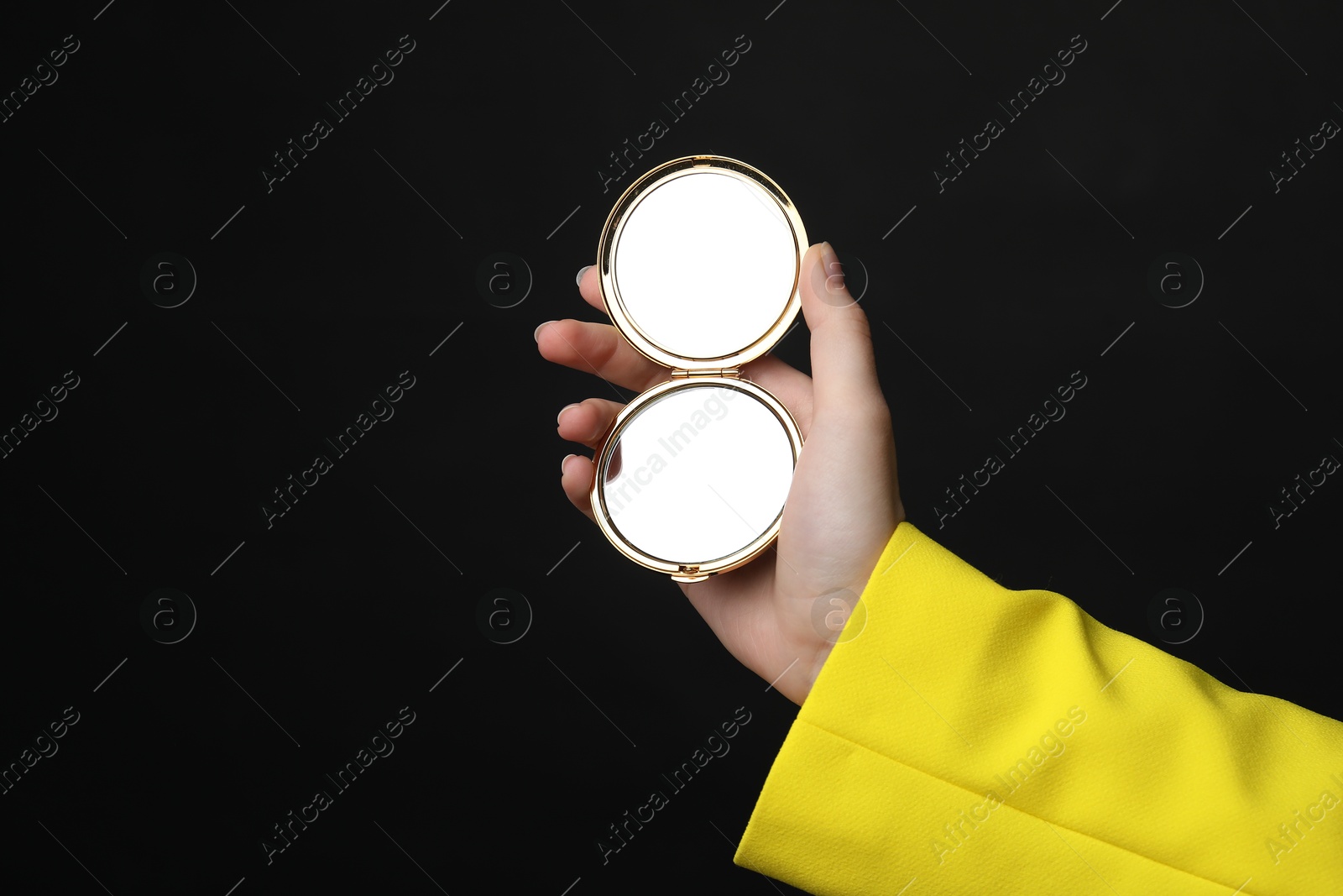 Woman holding open pocket mirror on black background, closeup Photo of Woman holding open pocket mirror on black background, closeup