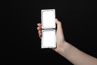 Photo of Woman holding open pocket mirror on black background, closeup
