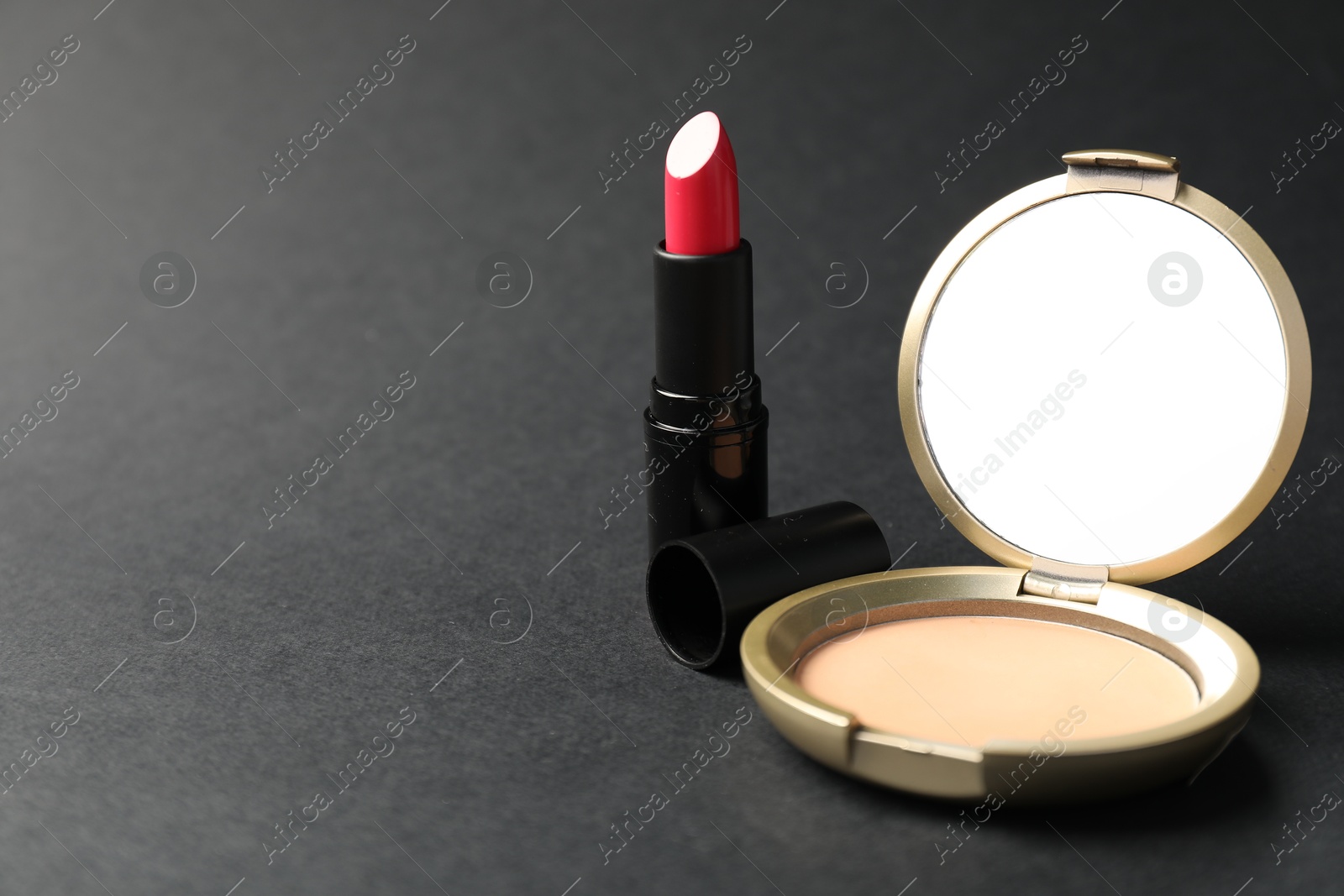Open face powder with mirror and lipstick on black background, closeup. Space for text Photo of Open face powder with mirror and lipstick on black background, closeup. Space for text