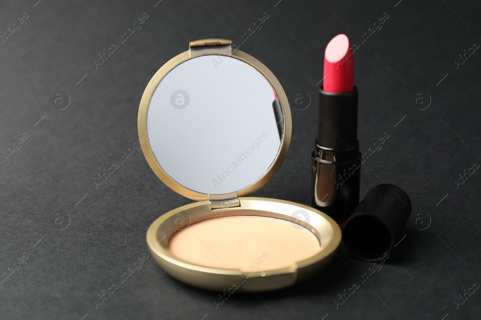 Open face powder with mirror and lipstick on black background, closeup Photo of Open face powder with mirror and lipstick on black background, closeup