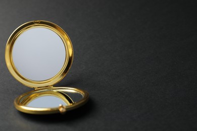 Photo of Open pocket mirror on black background, closeup. Space for text