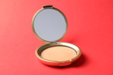 Photo of Open face powder with mirror on red background, closeup