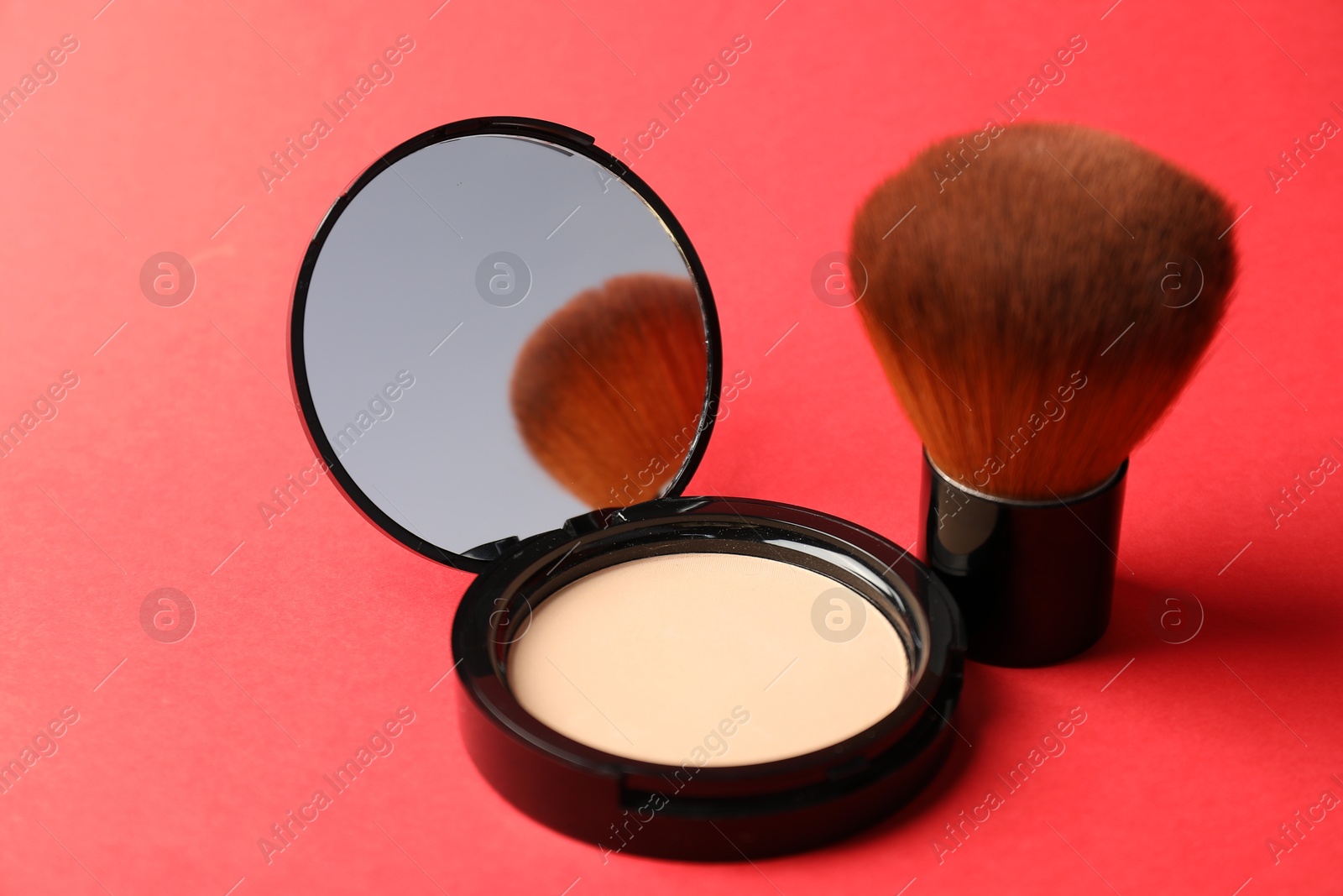 Open face powder with mirror and brush on red background, closeup Photo of Open face powder with mirror and brush on red background, closeup