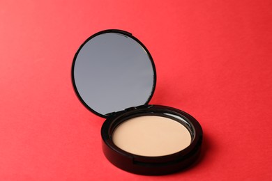 Photo of Open face powder with mirror on red background, closeup