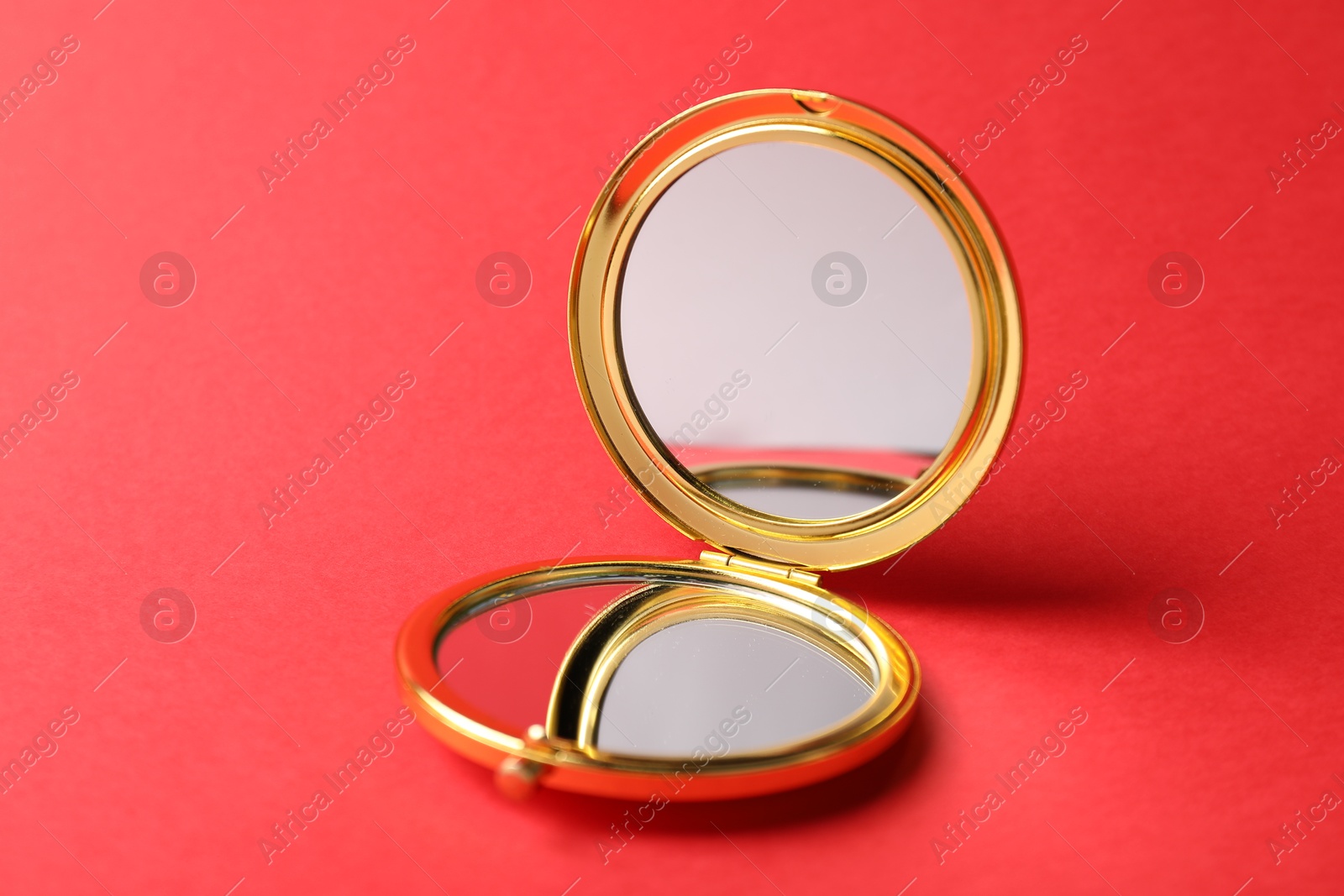 Open pocket mirror on red background, closeup Photo of Open pocket mirror on red background, closeup