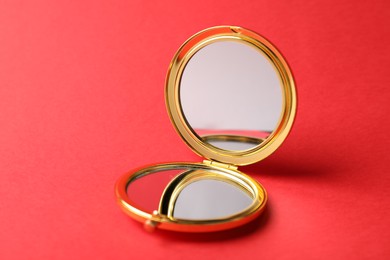 Photo of Open pocket mirror on red background, closeup