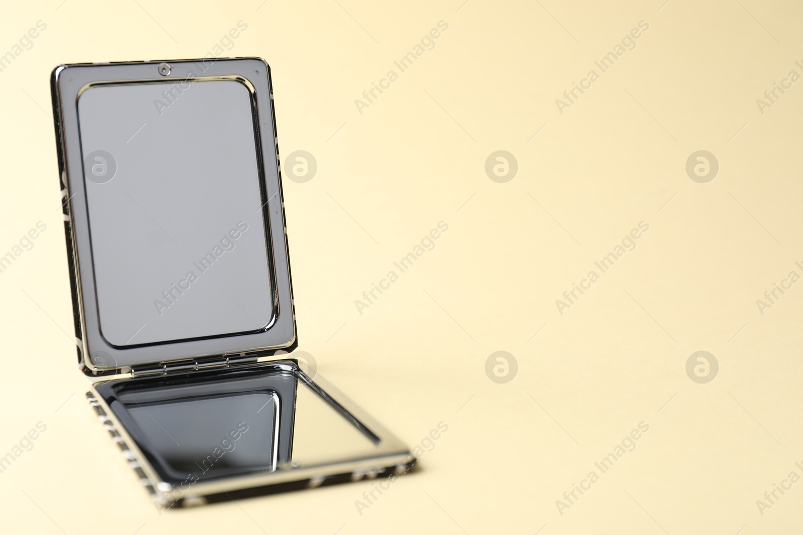 Open pocket mirror on beige background, closeup. Space for text Photo of Open pocket mirror on beige background, closeup. Space for text