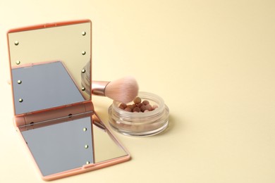 Photo of Open pocket mirror, brush and blush on beige background, closeup. Space for text