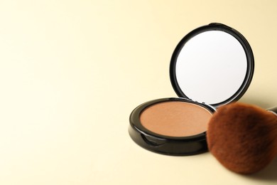 Photo of Open face powder with mirror and brush on beige background, closeup. Space for text
