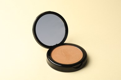 Photo of Open face powder with mirror on beige background, closeup