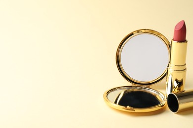 Photo of Open pocket mirror and lipstick on beige background, closeup. Space for text