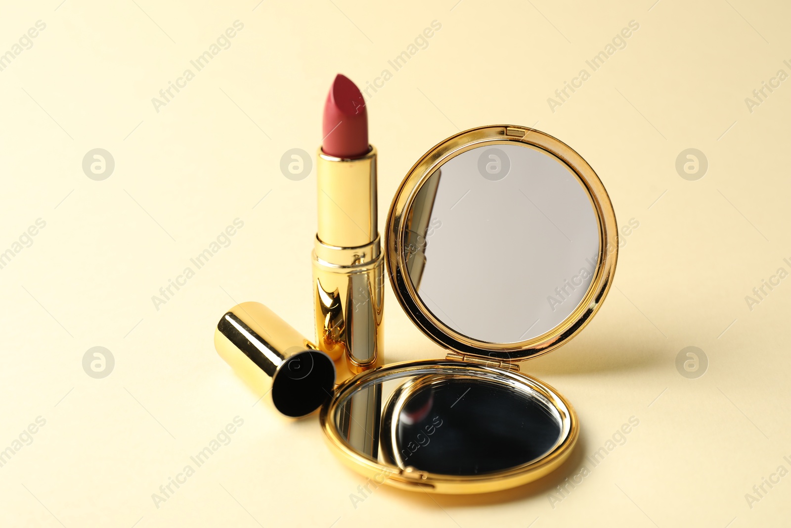 Open pocket mirror and lipstick on beige background, closeup Photo of Open pocket mirror and lipstick on beige background, closeup