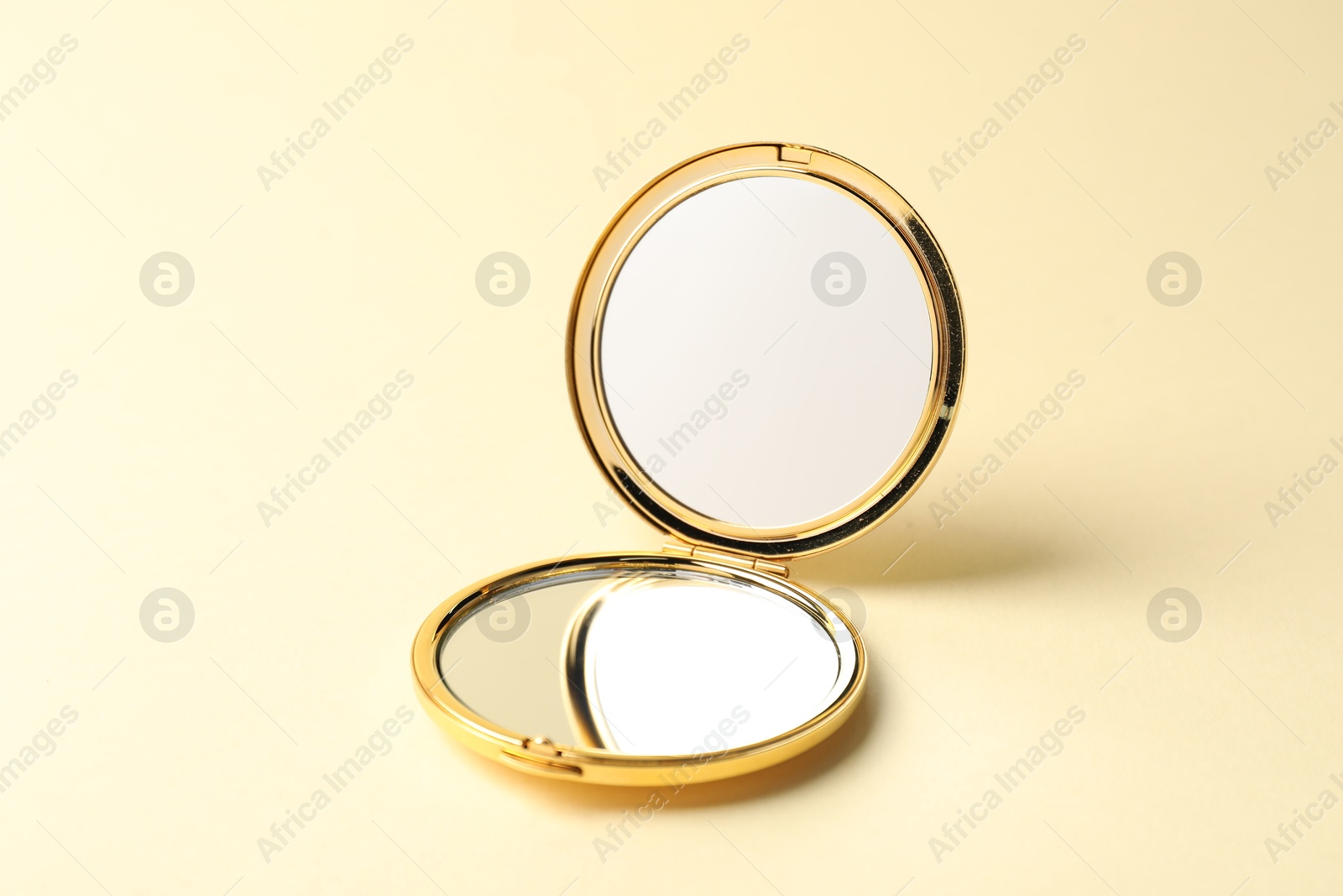 Open pocket mirror on beige background, closeup Photo of Open pocket mirror on beige background, closeup