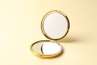 Photo of Open pocket mirror on beige background, closeup