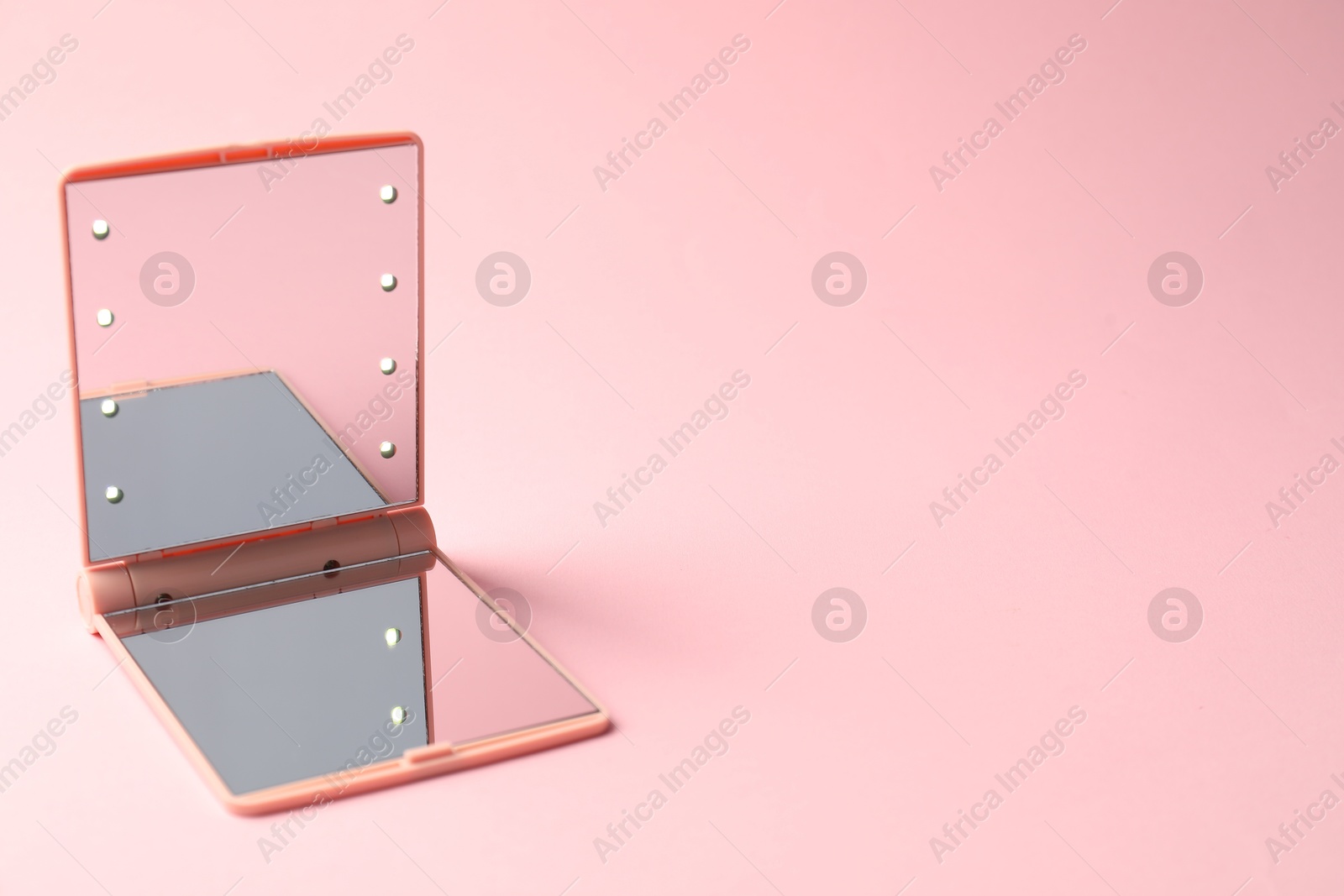 Open pocket mirror on pink background, closeup. Space for text Photo of Open pocket mirror on pink background, closeup. Space for text