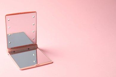 Photo of Open pocket mirror on pink background, closeup. Space for text