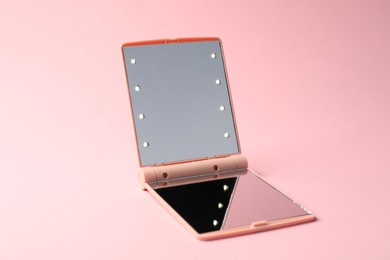 Photo of Open pocket mirror on pink background, closeup