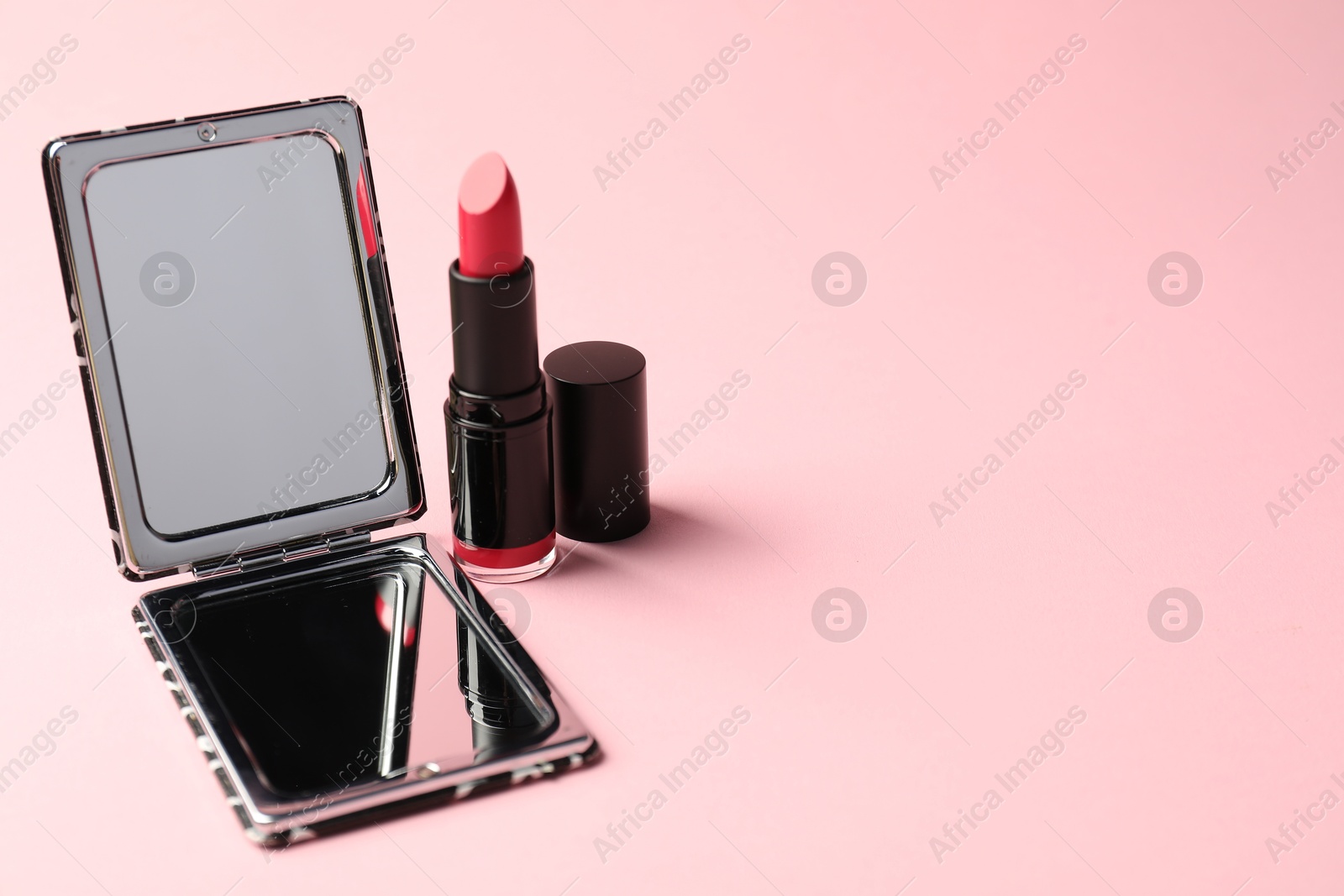 Photo of Open pocket mirror and lipstick on pink background, closeup. Space for text