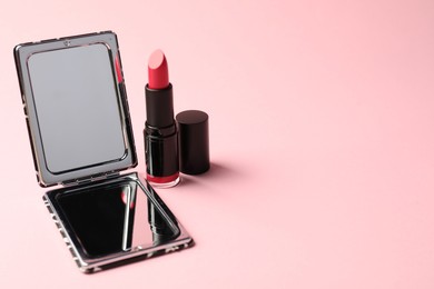 Photo of Open pocket mirror and lipstick on pink background, closeup. Space for text