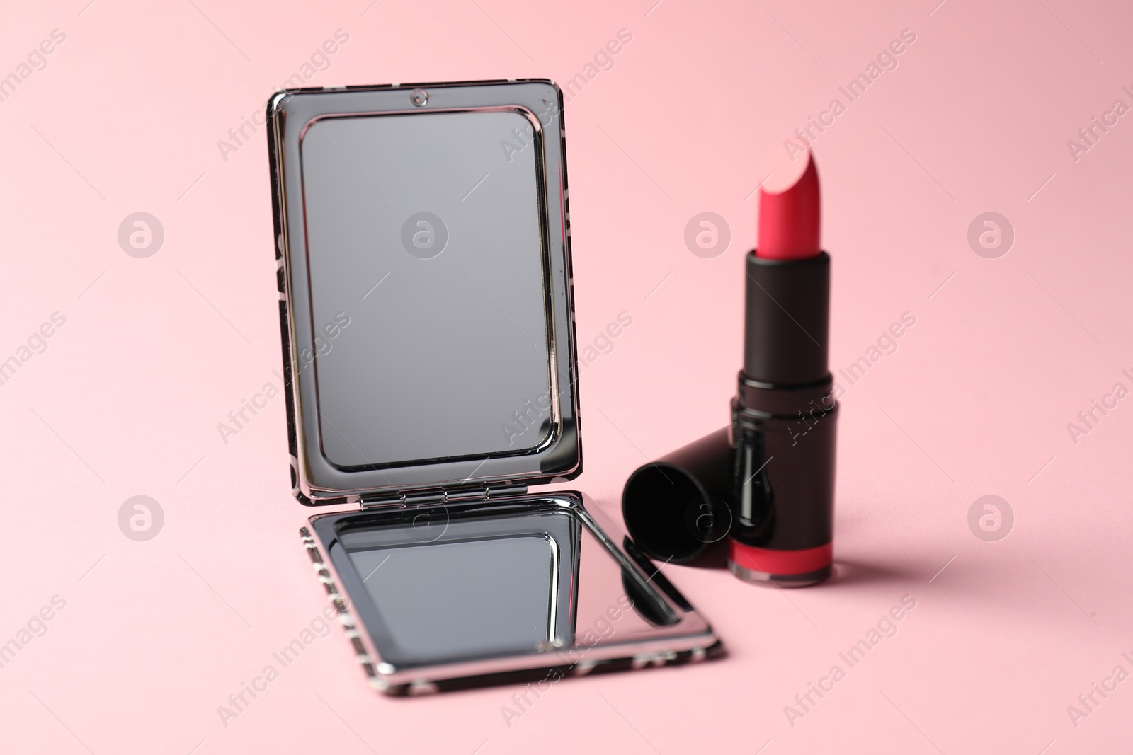 Open pocket mirror and lipstick on pink background, closeup Photo of Open pocket mirror and lipstick on pink background, closeup