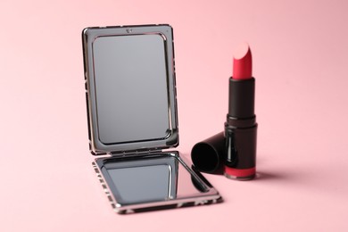 Photo of Open pocket mirror and lipstick on pink background, closeup