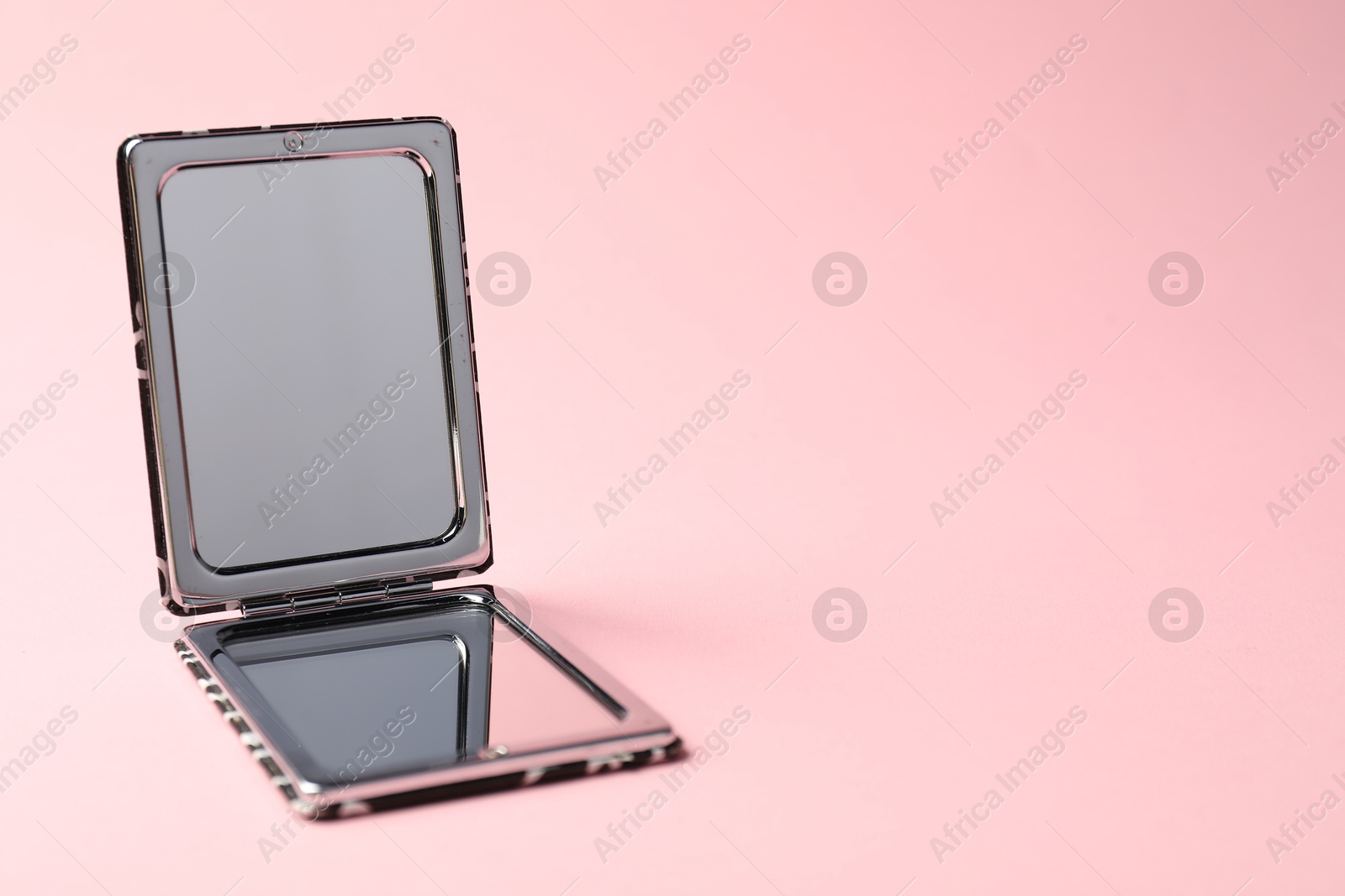 Open pocket mirror on pink background, closeup. Space for text Photo of Open pocket mirror on pink background, closeup. Space for text