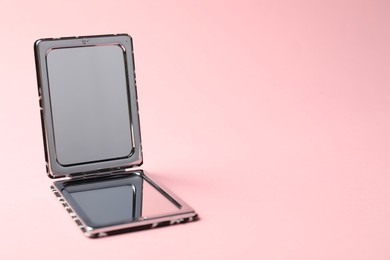 Photo of Open pocket mirror on pink background, closeup. Space for text