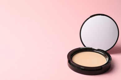 Photo of Open face powder with mirror on pink background, closeup. Space for text