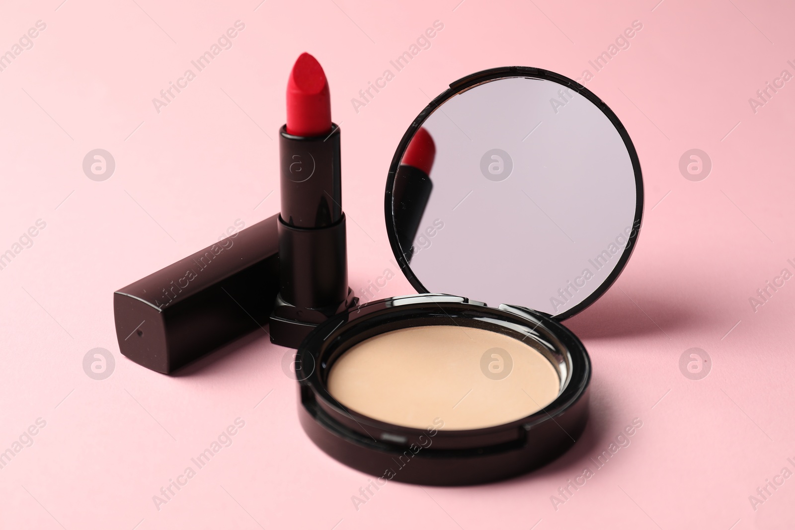 Photo of Open face powder with mirror and lipstick on pink background, closeup