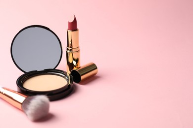 Photo of Open face powder with mirror, lipstick and brush on pink background, closeup. Space for text