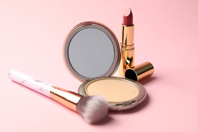 Photo of Open face powder with mirror, lipstick and brush on pink background, closeup
