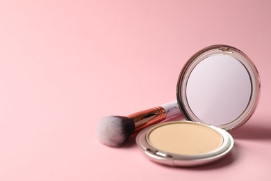 Photo of Open face powder with mirror and brush on pink background, closeup. Space for text