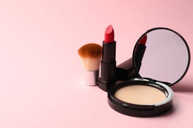 Photo of Open face powder with mirror, lipstick and brush on pink background, closeup. Space for text