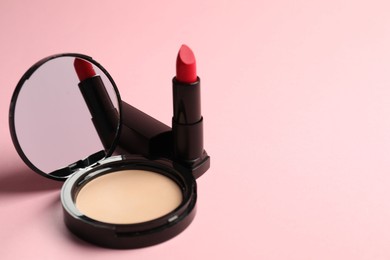 Photo of Open face powder with mirror and lipstick on pink background, closeup. Space for text