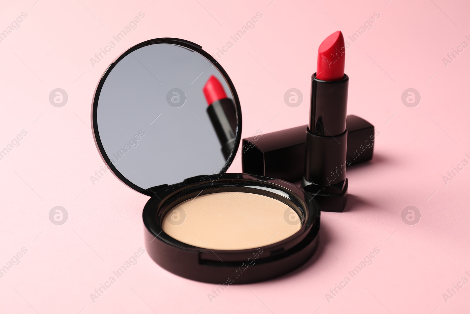 Open face powder with mirror and lipstick on pink background, closeup Photo of Open face powder with mirror and lipstick on pink background, closeup