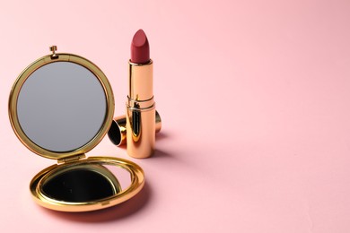 Photo of Open pocket mirror and lipstick on pink background, closeup. Space for text