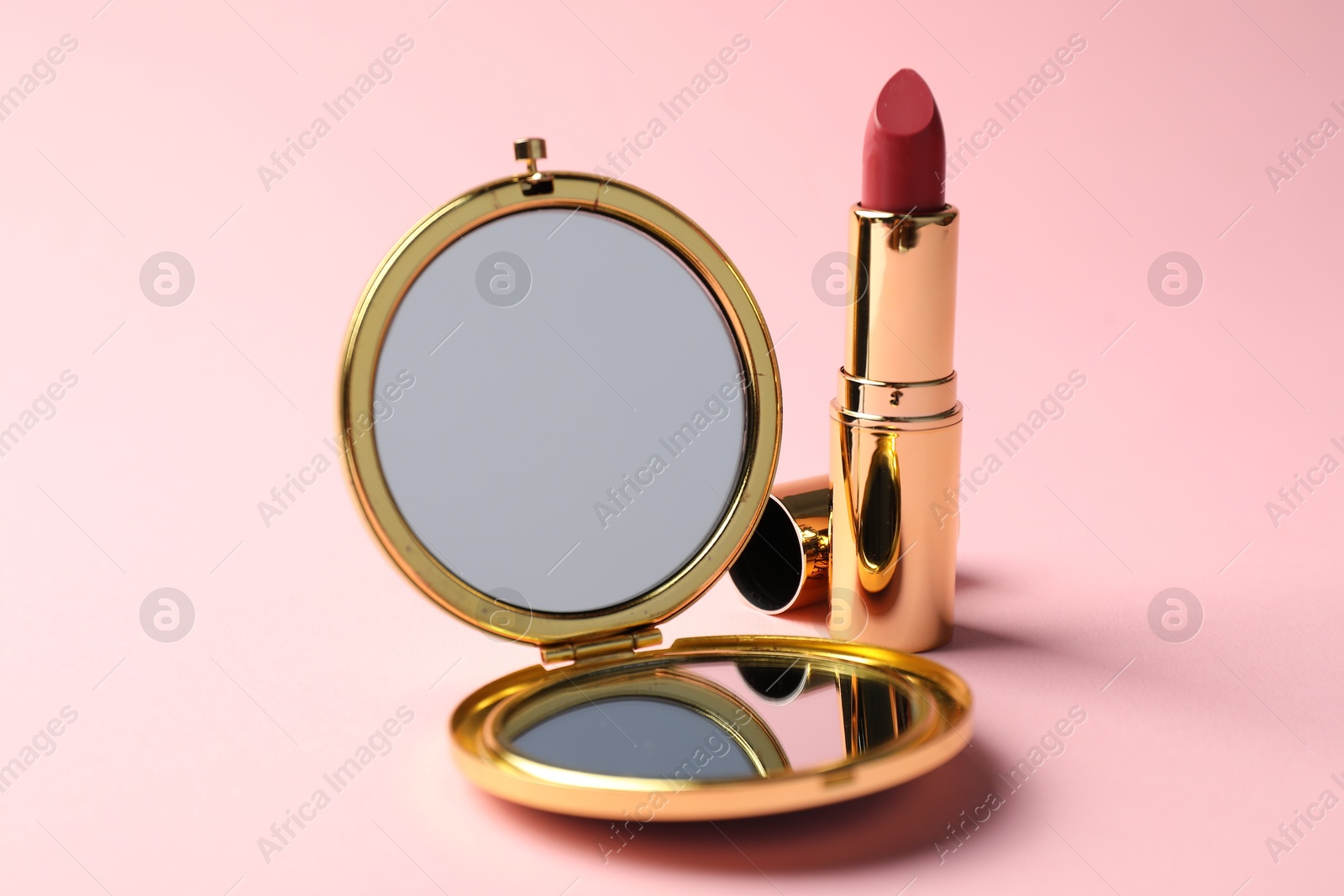 Open pocket mirror and lipstick on pink background, closeup Photo of Open pocket mirror and lipstick on pink background, closeup