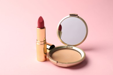 Photo of Open face powder with mirror and lipstick on pink background, closeup