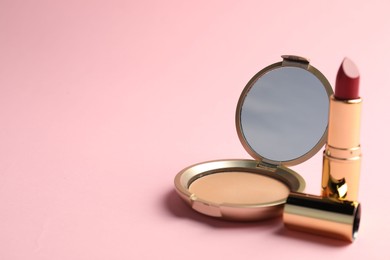 Photo of Open face powder with mirror and lipstick on pink background, closeup. Space for text