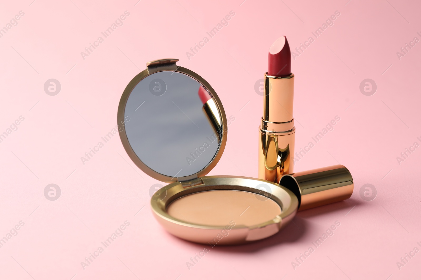 Open face powder with mirror and lipstick on pink background, closeup Photo of Open face powder with mirror and lipstick on pink background, closeup